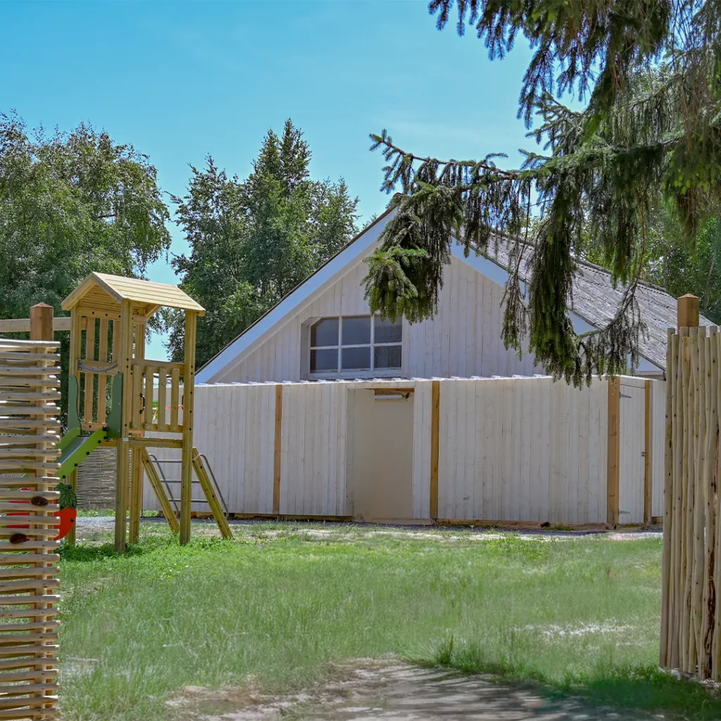 Tour de jeux en bois pour enfants devant la grange claire du camping