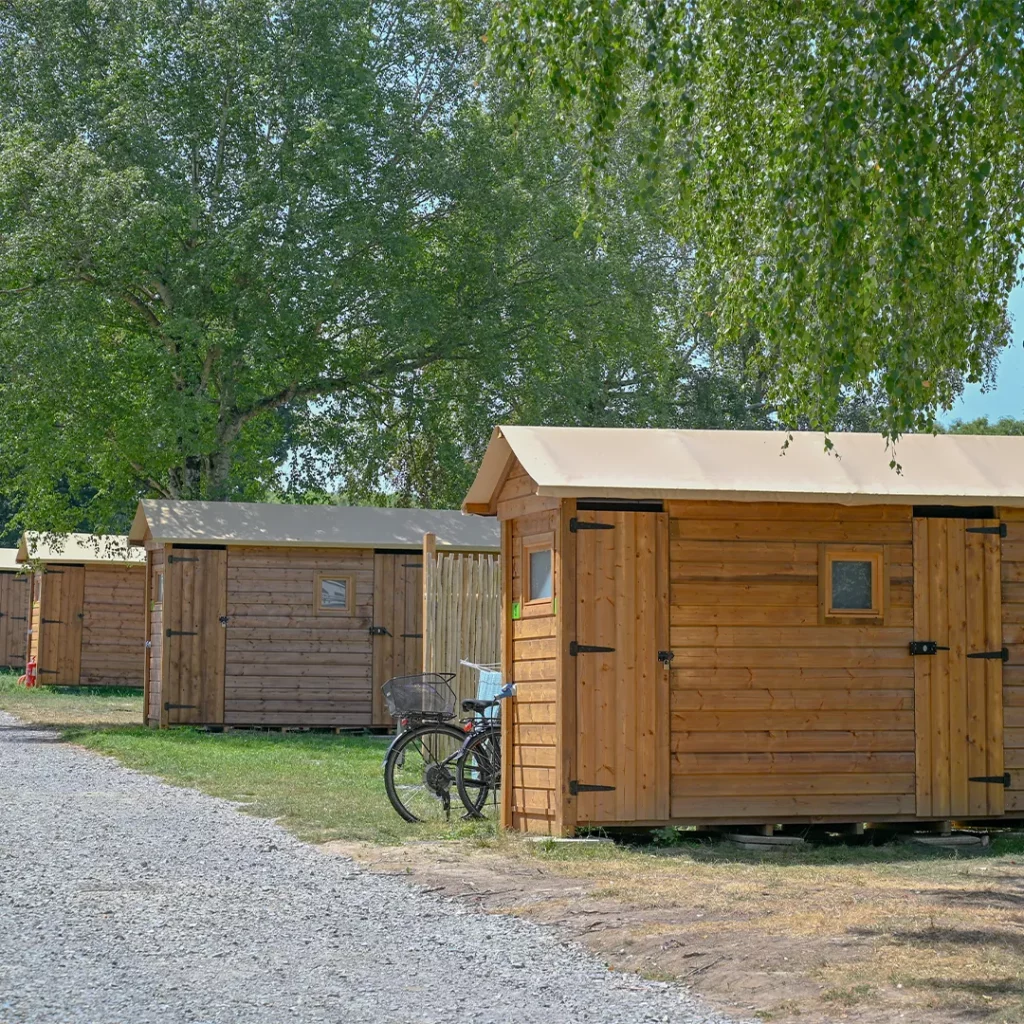 Vélo appuyé contre une cabane en bois à toit de toile, camping baie du Mont-Saint-Michel