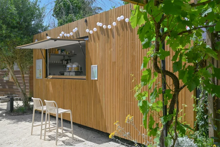 Comptoir en bois du snack avec tabourets et guirlande lumineuse, camping en Normandie