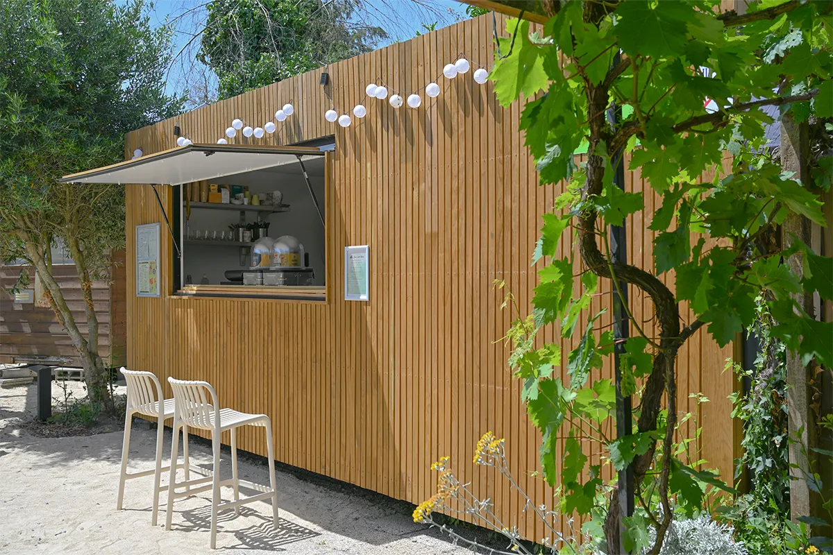 Comptoir en bois du snack avec tabourets et guirlande lumineuse, camping en Normandie