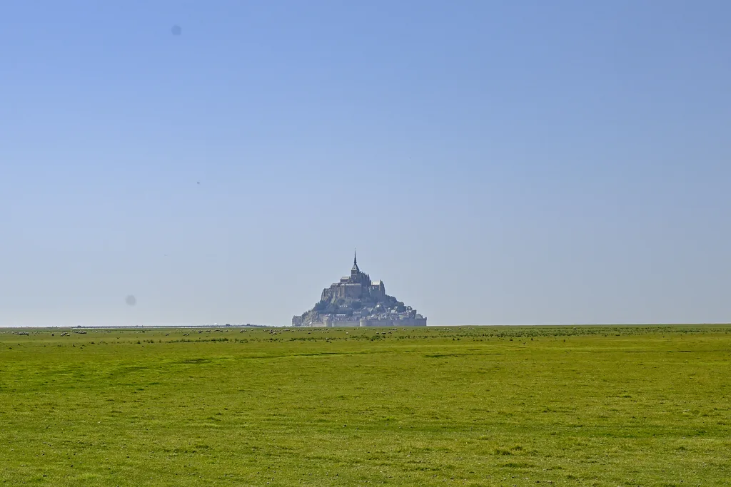 Le Mont-Saint-Michel se détache à l'horizon au-dessus des herbus de la baie