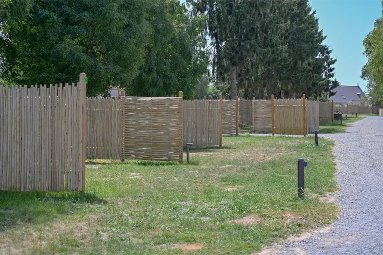 Palissades en bois et bornes électriques délimitant les emplacements de camping