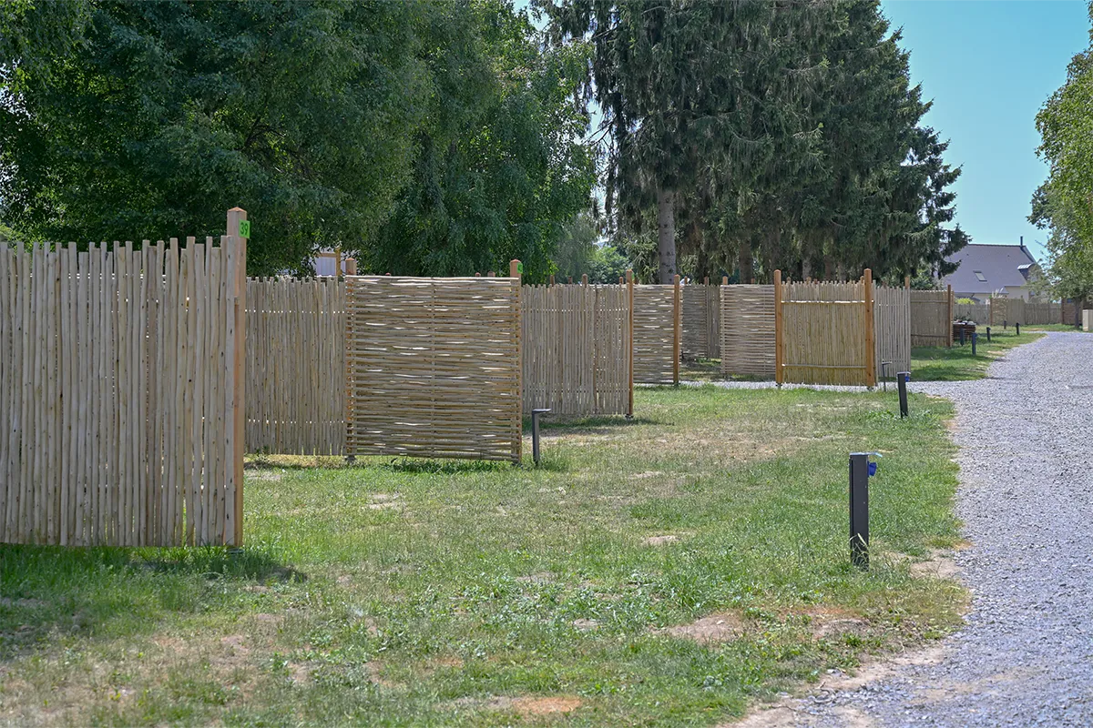 Palissades en bois et bornes électriques délimitant les emplacements de camping