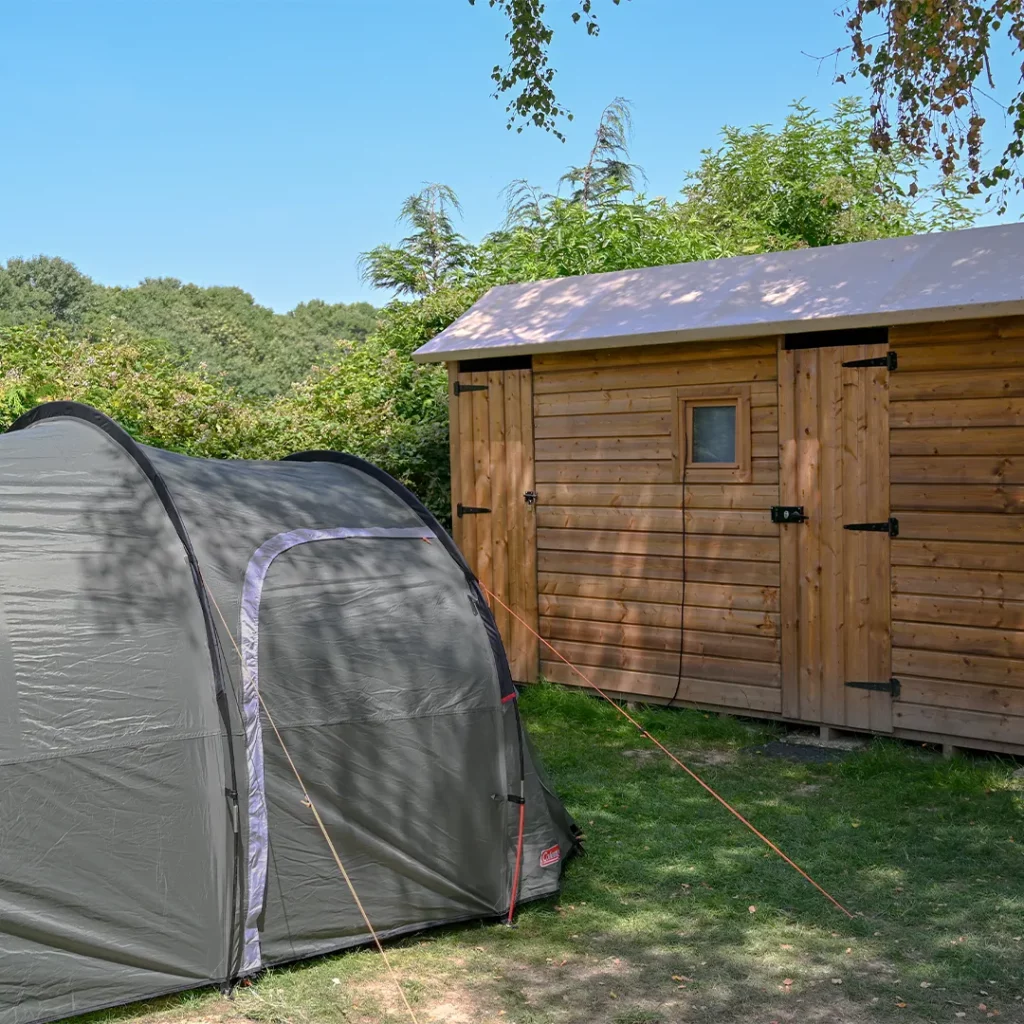 Tente grise montée à côté de sa cabane en bois privative, camping à Pontaubault
