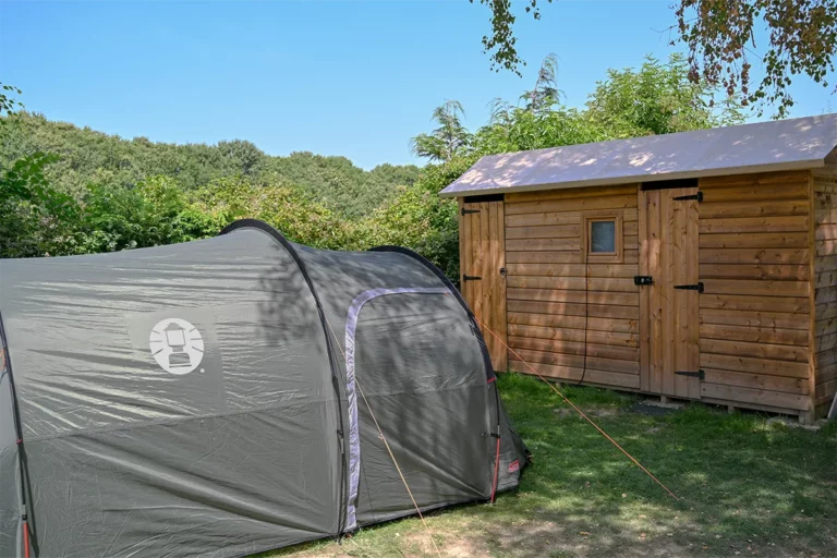 Tente familiale montée devant son cabanon en bois au camping à Pontaubault